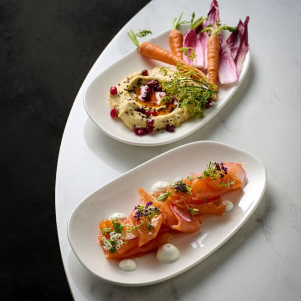 A serving of salmon and carrots with hummus, elegantly arranged on White Churchill Opal Platters, set on a marble tabletop