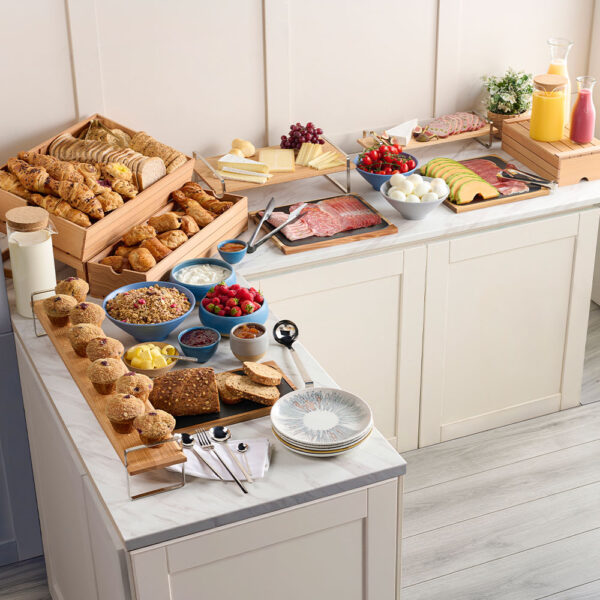 Comas Buffet items and Comas Utensils spread out in a buffet-style setting with bread, meats, and juices, using Churchill Emerge and Emerge Melamine to present fruit and yoghurt