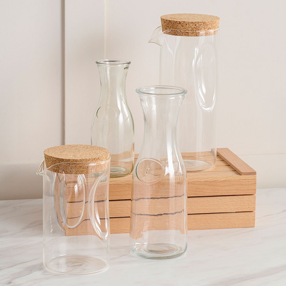 Clear Comas Buffet Jugs and Bottles with brown lids, displayed on a Comas Wooden Box