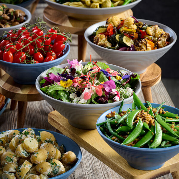 Churchill Emerge Melamine Ripple Bowls in Seattle Grey and Oslo Blue, used to present colourful salads, scattered across a tabletop