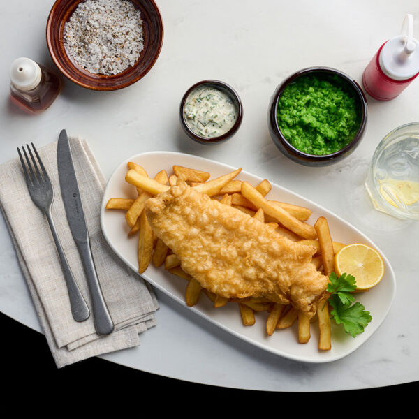 Fish and chips dish presented on Churchill Opal White Opal Platters, set on a marble table surrounded by napkins and condiments