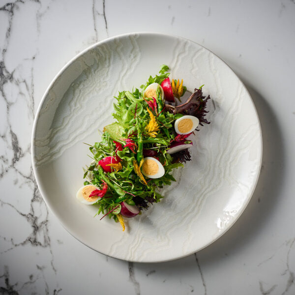Churchill Inked Tide White Coupe Plate, presenting a bright and colourful egg salad on a marble tabletop