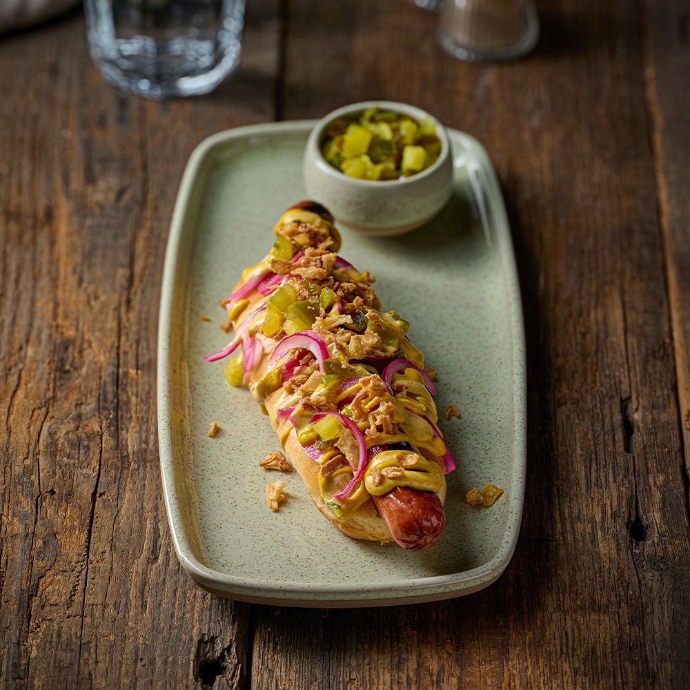 Churchill Emerge Speckled Green natural deep tray with hot dog on rustic tabletop